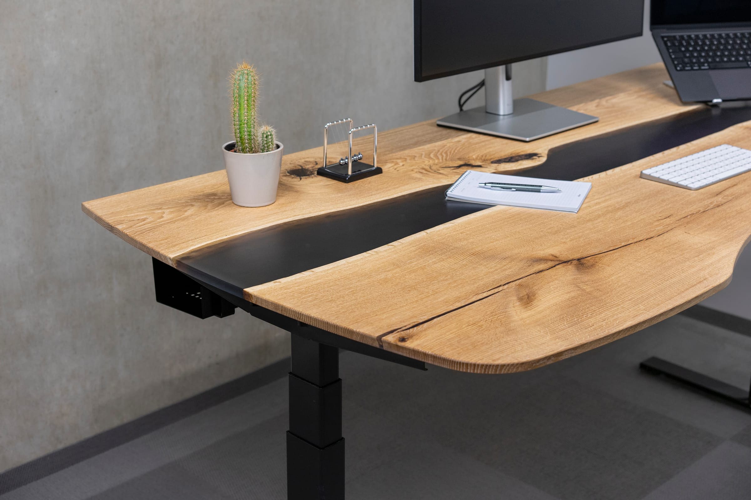 Oak slab desk top with a black epoxy river on a black electric frame